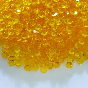 May include: A pile of small, round, yellow, clear plastic gems.
