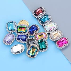 May include: Assortment of colorful rectangular rhinestones with silver settings. The rhinestones are surrounded by clear rhinestones.