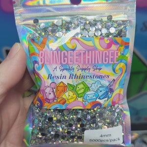 May include: A clear plastic bag filled with 4mm silver resin rhinestones. The bag has a label that reads "BlingEeThingEe A Sparkly Supply Shop Resin Rhinestones 4mm 5000pcs/pack".
