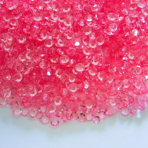 May include: A large pile of pink iridescent glass beads. The beads are round and have a shiny finish.