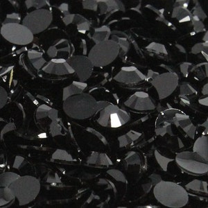 May include: A close-up image of a large quantity of black rhinestones. The rhinestones are faceted and have a shiny finish.