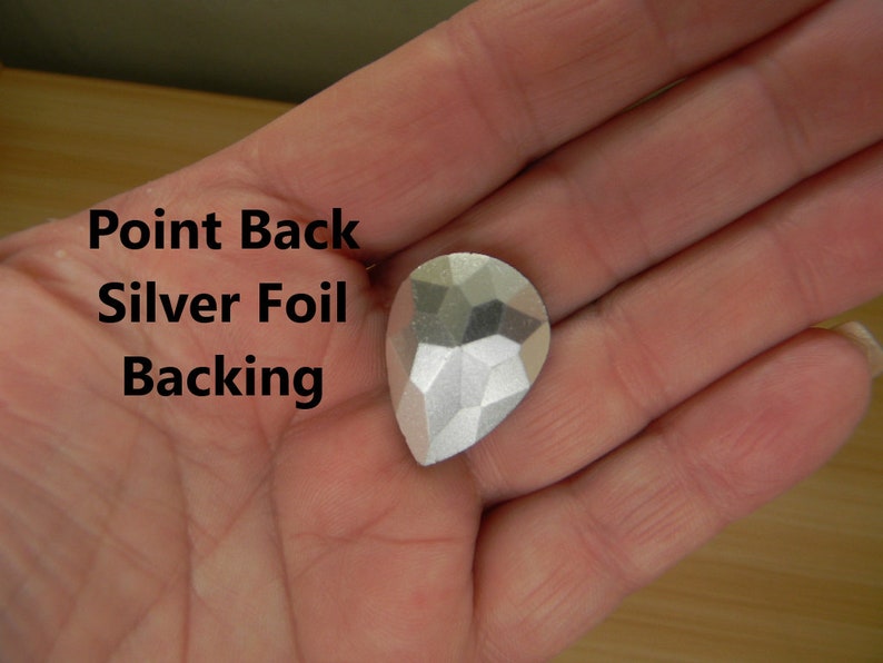 May include: A silver teardrop-shaped rhinestone with a pointed back and silver foil backing.  Point Back Silver Foil Backing.