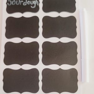 May include: A sheet of eight black chalkboard labels with a white border and a scalloped edge. The labels are blank except for one that says "Sourdough". A white dry-erase marker is included.