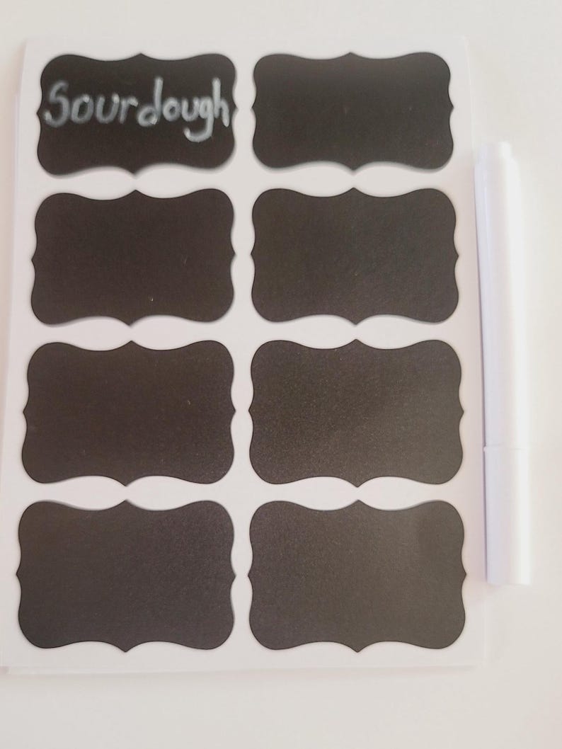 May include: A sheet of eight black chalkboard labels with a white border and a scalloped edge. The labels are blank except for one that says "Sourdough". A white dry-erase marker is included.