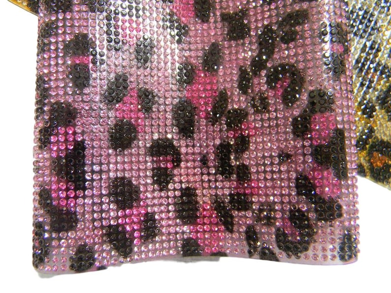 May include: Pink and black leopard print fabric covered in small, clear rhinestones.