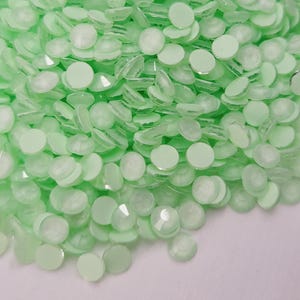May include: A large pile of light green round flatback rhinestones.