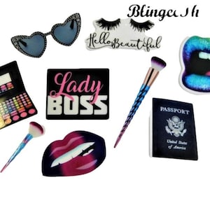 Può includere: Un set di toppe termoadesive decorative colorate che rappresentano trucco, occhiali da sole, labbra, un passaporto, un pennello per il trucco e una toppa bianca e nera con il testo "Lady Boss".