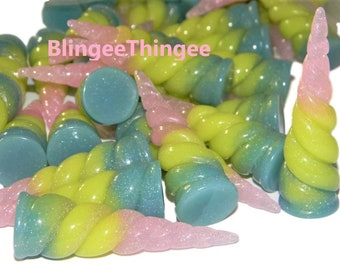 May include: A group of pastel pink, yellow, and blue unicorn horn charms with glitter. The horns are twisted and have a gradient color effect. The charms are made of resin and are perfect for adding a whimsical touch to any craft project.