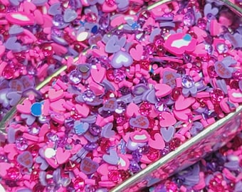 May include: A scoop of pink and purple heart-shaped sprinkles, with some sprinkles that say "I love you" and "Kiss Me".