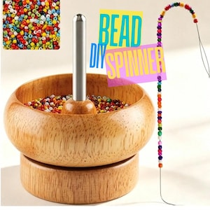 May include: A wooden bead spinner with a central metal spindle, filled with small multicolored seed beads. The text "DIY BEAD SPINNER" is displayed in blue and yellow. A long needle with a string of colorful beads is positioned to the right.