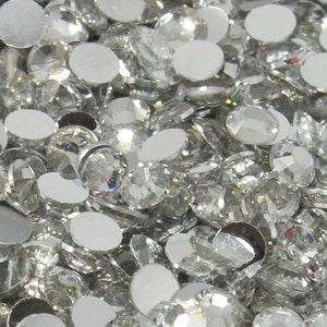 May include: A large quantity of clear, faceted rhinestones with a silver backing. The rhinestones are scattered randomly.