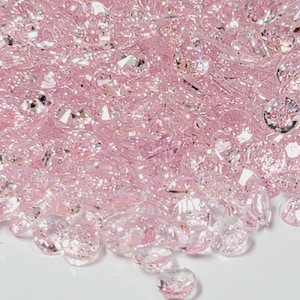 May include: A pile of pink iridescent glass crystals, perfect for adding sparkle to crafts and decorations.