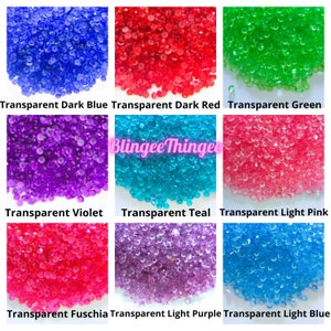 Puede incluir: Surtido de gemas de plástico transparentes, redondas, facetadas, en varios colores, incluyendo azul oscuro, rojo oscuro, verde, violeta, turquesa, rosa claro, fucsia, morado claro y azul claro. Las gemas están dispuestas en una cuadrícula de nueve cuadrados.