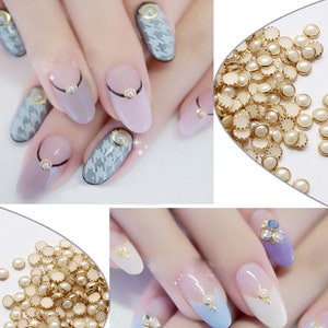 May include: A close-up of a set of white pearl nail charms with gold accents. The charms are scattered on a white surface. The charms are also shown on a set of manicured nails.