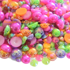 Op de afbeelding: Assortiment van kleurrijke, iriserende en ondoorzichtige ronde en halfronde cabochons in roze, groen, oranje en paars.