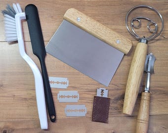 以下が含まれることがあります： 木製ハンドル付きの生地スクレーパー、木製ハンドル付きの泡立て器、白黒のハンドル付きのブラシ、そして3枚の剃刀の刃を含むキッチンツールのセットです。