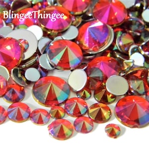 Puede incluir: Surtido de piedras de cristal rojas iridiscentes en varios tamaños. Las piedras de cristal tienen un diseño facetado y un acabado brillante.