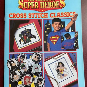 May include: A light blue leaflet titled "DC Comics Super Heroes Cross Stitch Classics" featuring cross-stitch patterns of Batman, Wonder Woman, and other DC characters. The leaflet includes a photo of a person wearing a Superman t-shirt.