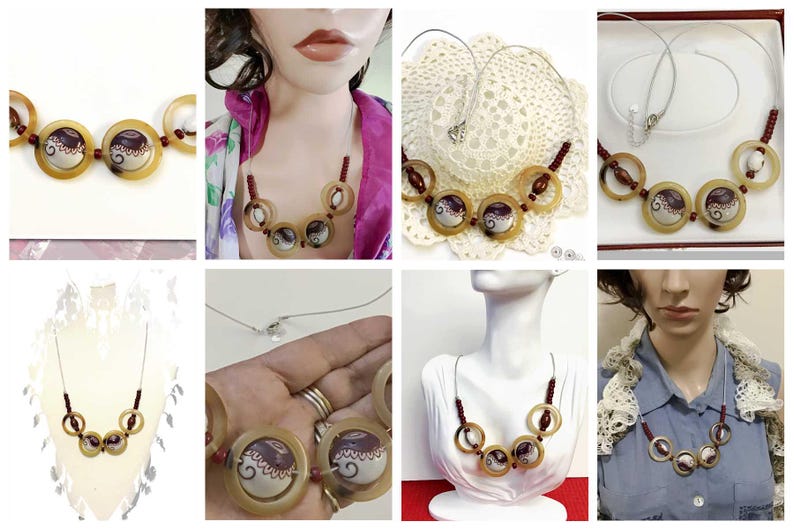 May include: A necklace featuring a series of circular horn-colored rings, interspersed with small dark red beads and two central circular pendants decorated with a white and dark brown swirl pattern, all strung on a thin silver-toned wire cord.