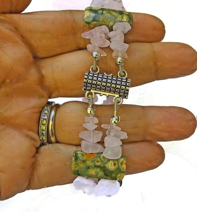 May include: A handmade bracelet featuring alternating sections of light pink rose quartz chips and green jasper stones. The bracelet is connected with silver-toned metal links and a decorative clasp.