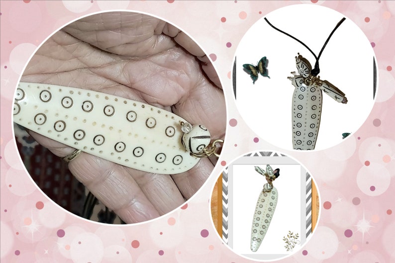 May include: Ivory-colored pendant necklace with a black cord. The pendant is elongated with a series of small, dark circles and a decorative bead. A butterfly is near the pendant. The necklace is handmade.
