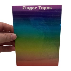 以下が含まれることがあります： 前面に「Finger Tapes」と印刷された、カラフルな指用テープの詰め合わせです。