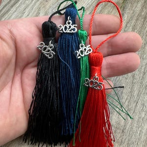 May include: Four graduation tassels in black, blue, green, and red with silver charms that say "2025".