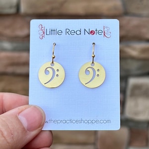 May include: Gold bass clef earrings on a white card with the text "Little Red Note" and "www.thepracticeshoppe.com".