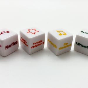 May include: Six white dice with red, green, and yellow text. The dice feature musical notes, a star, and the titles of songs, including "Mary Had a Little Lamb", "Fireflies", "Twinkle Variation A", "Twinkle Variation B", "The Honeybee", "Amaryllis", "Bourree", and "Minuet 3".