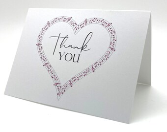 May include: A white card with a pink musical note heart design. The text "Thank You" is written in black inside the heart.
