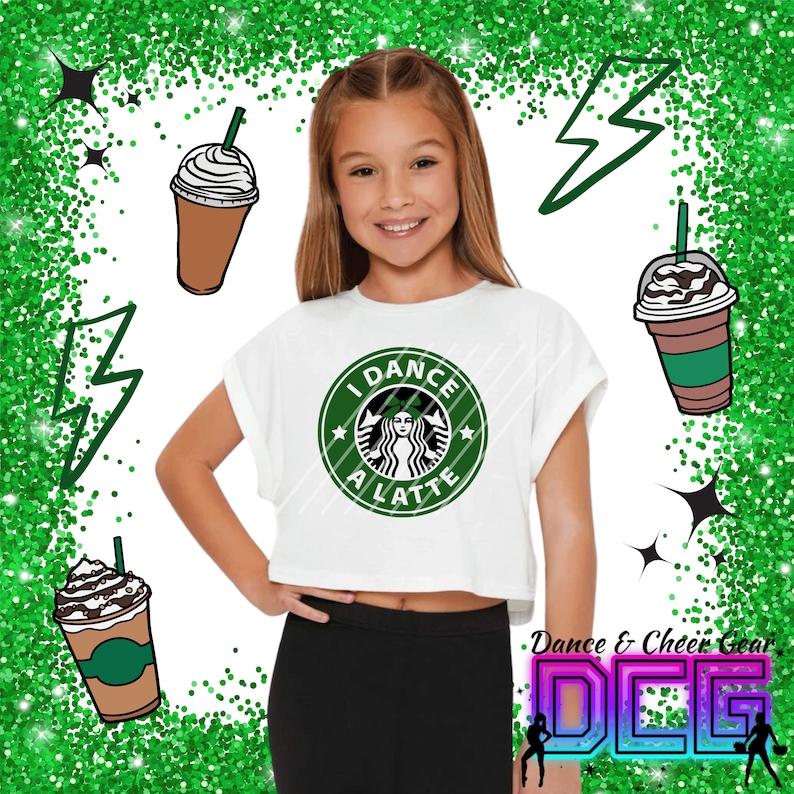 May include: A white crop top with a green and white graphic of a coffee cup with the text "I Dance A Latte". The model is wearing black leggings and has a green glitter background.