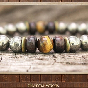 May include: A beaded bracelet featuring a repeating pattern of metallic pyrite spheres, dark brown wooden beads, and brass-toned spacers, centered with a single polished tiger eye bead that displays a distinct golden-brown chatoyant band.