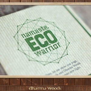 May include: A green and white logo with the text "namaste, ECO Warrior" inside a geometric shape. The logo is printed on a brown paper background.