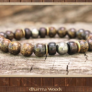 May include: A brown and gold beaded bracelet with a silver bead accent. The bracelet is made of natural materials and has a rustic look.