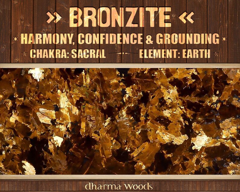 May include: Close-up of a golden brown bronzite crystal. The text ">>> BRONZITE <<< HARMONY, CONFIDENCE & GROUNDING CHAKRA: SACRAL ELEMENT: EARTH dharma woods" is visible at the top and bottom of the image.