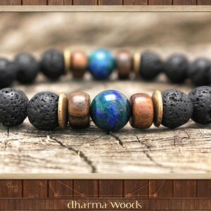 May include: A beaded bracelet featuring a central polished blue and green marbled sphere, flanked by two brown wooden beads and two brass-toned metal spacers, followed by a series of porous black lava stone beads arranged in a circular pattern.