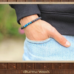 May include: A beaded bracelet featuring a series of textured black lava stone beads, interspersed with a segment of smooth, vibrant blue and turquoise spherical beads, accented by small metallic copper-toned spacers on an elastic cord.