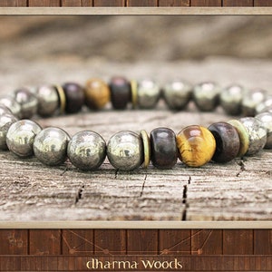 May include: A beaded bracelet featuring metallic silver-toned spherical beads, dark brown wooden beads, and a single golden-brown tiger eye bead. The beads are arranged in a circular pattern with small brass-coloured spacers between the segments.