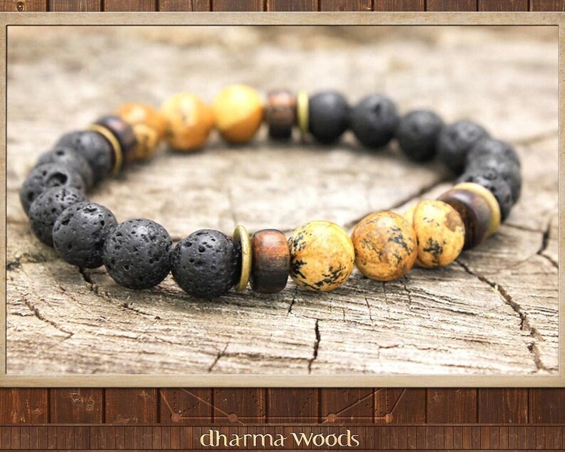 May include: A beaded bracelet featuring a repeating pattern of porous black lava stone beads, smooth tan and brown speckled jasper beads, dark brown wooden cylindrical beads, and thin metallic brass spacers arranged in a circular design.