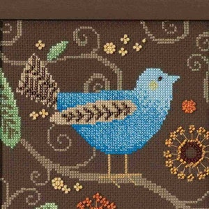 May include: Framed cross-stitch artwork featuring a blue bird perched on a branch. The bird has a detailed wing pattern and is surrounded by floral and leaf motifs in shades of green, orange, and yellow against a brown background. The frame is brown.