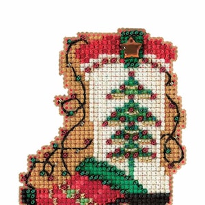 May include: A Christmas ornament shaped like a cowboy boot, featuring a cross-stitch design. The boot is primarily red, brown, and white, with a green Christmas tree and string lights. A small star adorns the top.