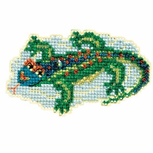May include: A cross-stitch design of a lizard in shades of green, blue, and orange. The lizard is detailed with small beads and is set against a light blue background. The lizard's tongue is red.