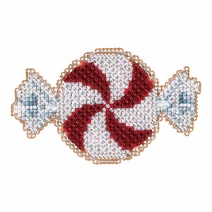 May include: A cross-stitched candy design with red and white stripes in the center, wrapped in a silver-colored wrapper. The candy has a gold-colored, scalloped border. The image is set against a white background.