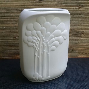 May include: White ceramic vase with a raised design of a stylized tree with rounded leaves.