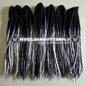 May include: A set of synthetic dreadlocks featuring a black to grey ombre color gradient. The hair extensions are arranged in parallel rows. Overlaid text reads NVCL3ARBVTT3RFLY designs by Cheyenne Le Hale with two butterfly icons on the sides.