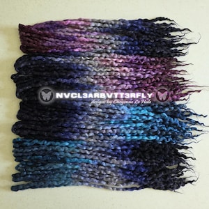 May include: A collection of synthetic hair extensions featuring a wavy, twisted texture with a gradient color palette of deep purple, midnight blue, and bright cyan. The text NVCL3ARBVTT3RFLY designs by Cheyenne Le Hale is centered on the image.