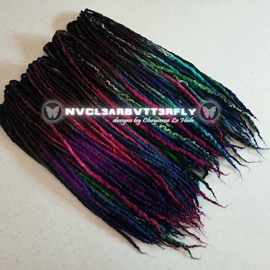 Könnte beinhalten: Ein Bündel bunter Dreadlocks in Schwarz, Rot, Lila, Grün und Blau. Die Dreadlocks sind in einem geschichteten Muster angeordnet. Der Text "NVCL3ARBVTT3RFLY designs by Cheyenne Le Hale" ist sichtbar.