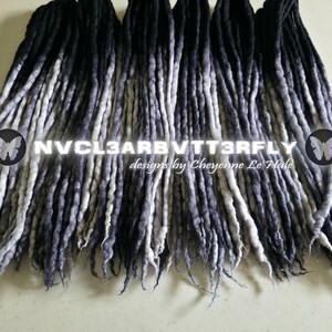 May include: A collection of synthetic dreadlocks featuring an ombre color transition from black at the roots to a light grey at the tips. The text NVCL3ARBVTT3RFLY designs by Cheyenne Le Hale is centered across the strands with butterfly icons.