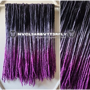 Könnte beinhalten: Ein Set synthetischer Dreadlocks in Ombre-Optik in Schwarz, Grau und Lila. Die Dreadlocks hängen an einer weißen Oberfläche und haben oben ein Schmetterlingsdesign. Der Text "NVCL3ARBVTTR3FLY designs by Cheyenne Le Hale" ist auf den Dreadlocks sichtbar.