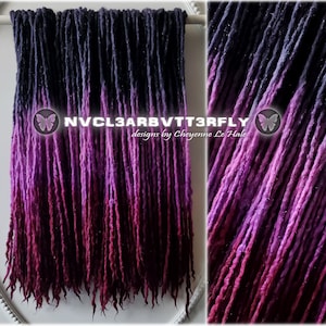 May include: Handmade dreadlocks in a colour gradient, fading from dark blue to purple and deep red. The text "NVCL3ARBVTT3RFLY designs by Cheyenne Le Hale" is displayed. The dreadlocks are displayed on a white background.